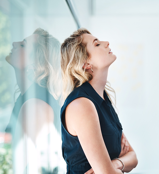 Woman leans against window and closes eyes