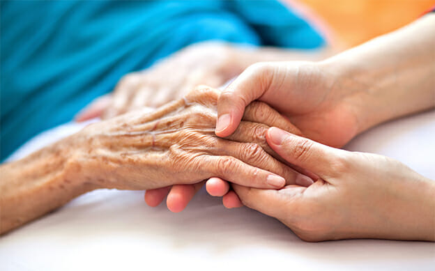 Frau hält die Hand einer älteren Frau