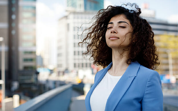 Businesswoman takes a deep breath outdoors