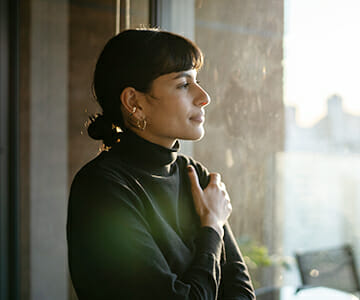 Young woman standing by window at home