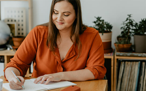 Woman sitting at her desk and writing a journal