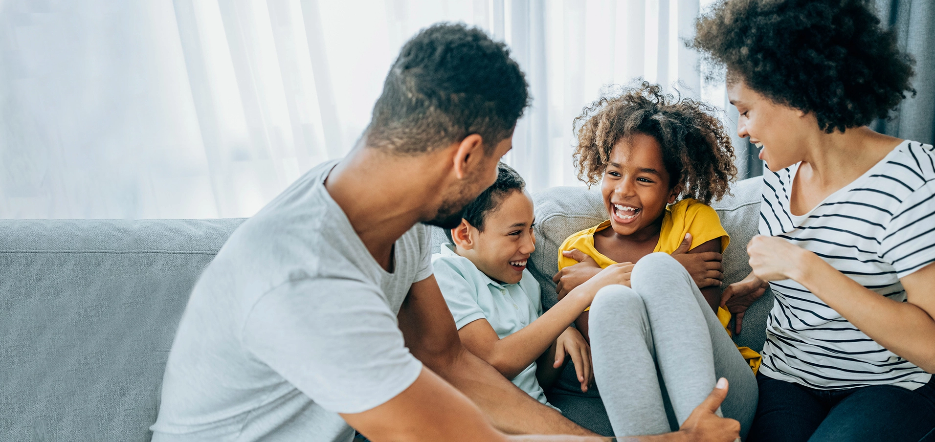 Glückliche Familie mit Eltern und Kindern sitzt lachend auf Sofa