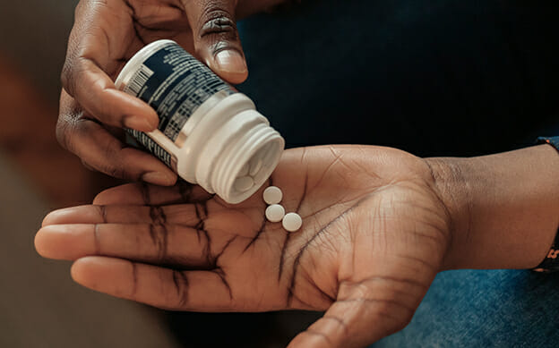 Person taking pills from a bottle