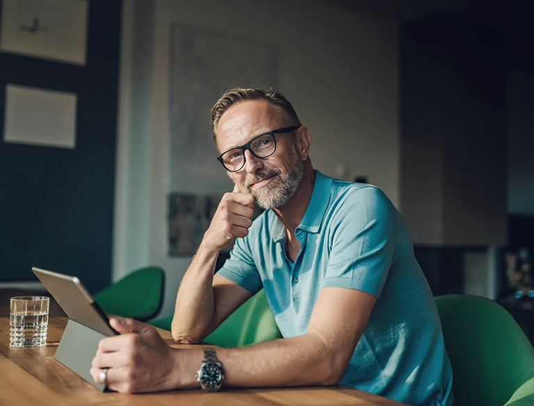 Lächelnder Mann am Tisch mit Tablet