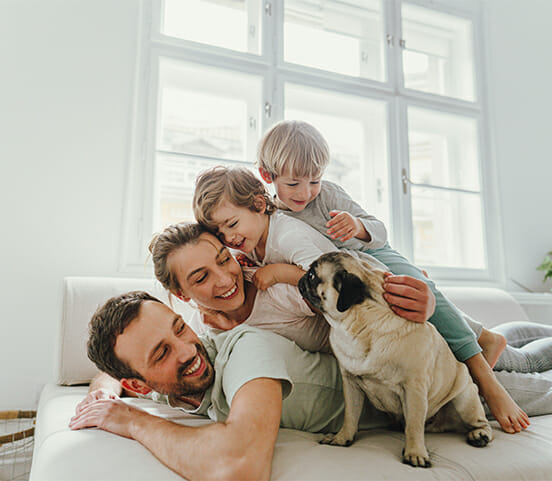 family with two kids lying on the top of each other being cheerful and playful {:de}