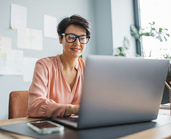 Woman with glasses sits in front of laptop