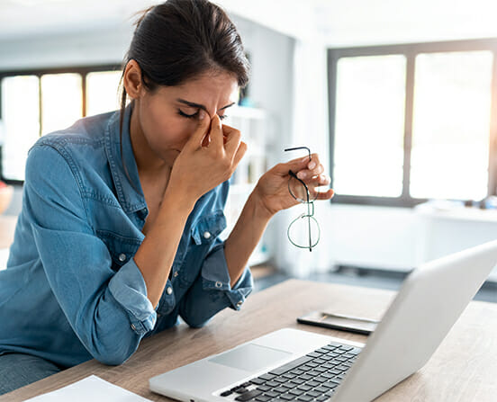 Stressed business woman working from home on laptop looking worried, tired and overwhelmed.