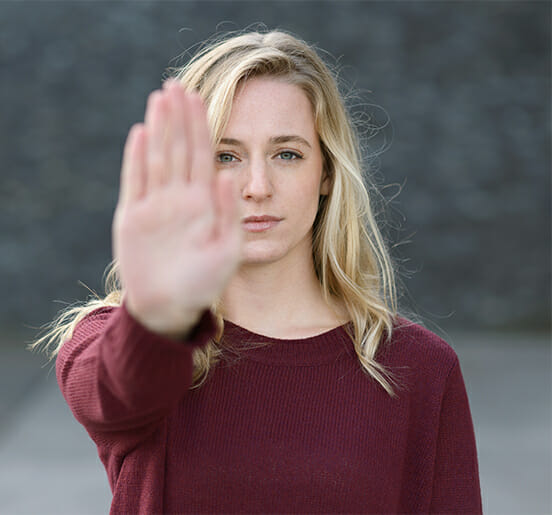 Frau, die mit ihrer erhobenen Hand eine Stopp-Geste macht