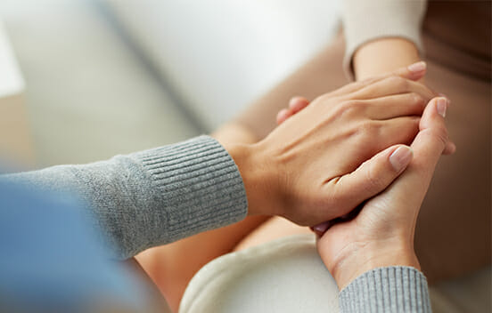 Woman comfortingly holding the hand of another person
