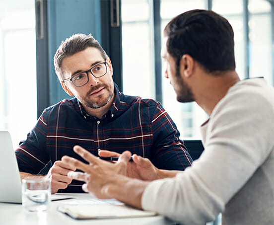 Zwei Kollegen sitzen am Tisch und diskutieren