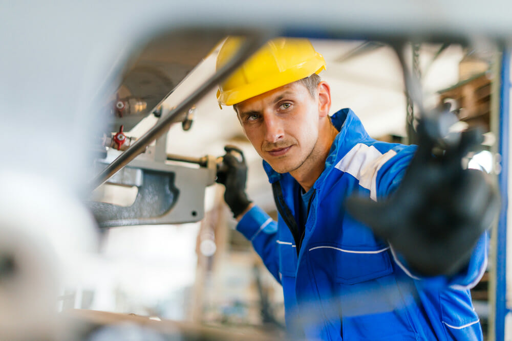 Man in overalls works in workshop