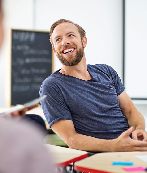 Mann sitzt am Tisch und spricht mit Arbeitskollegen