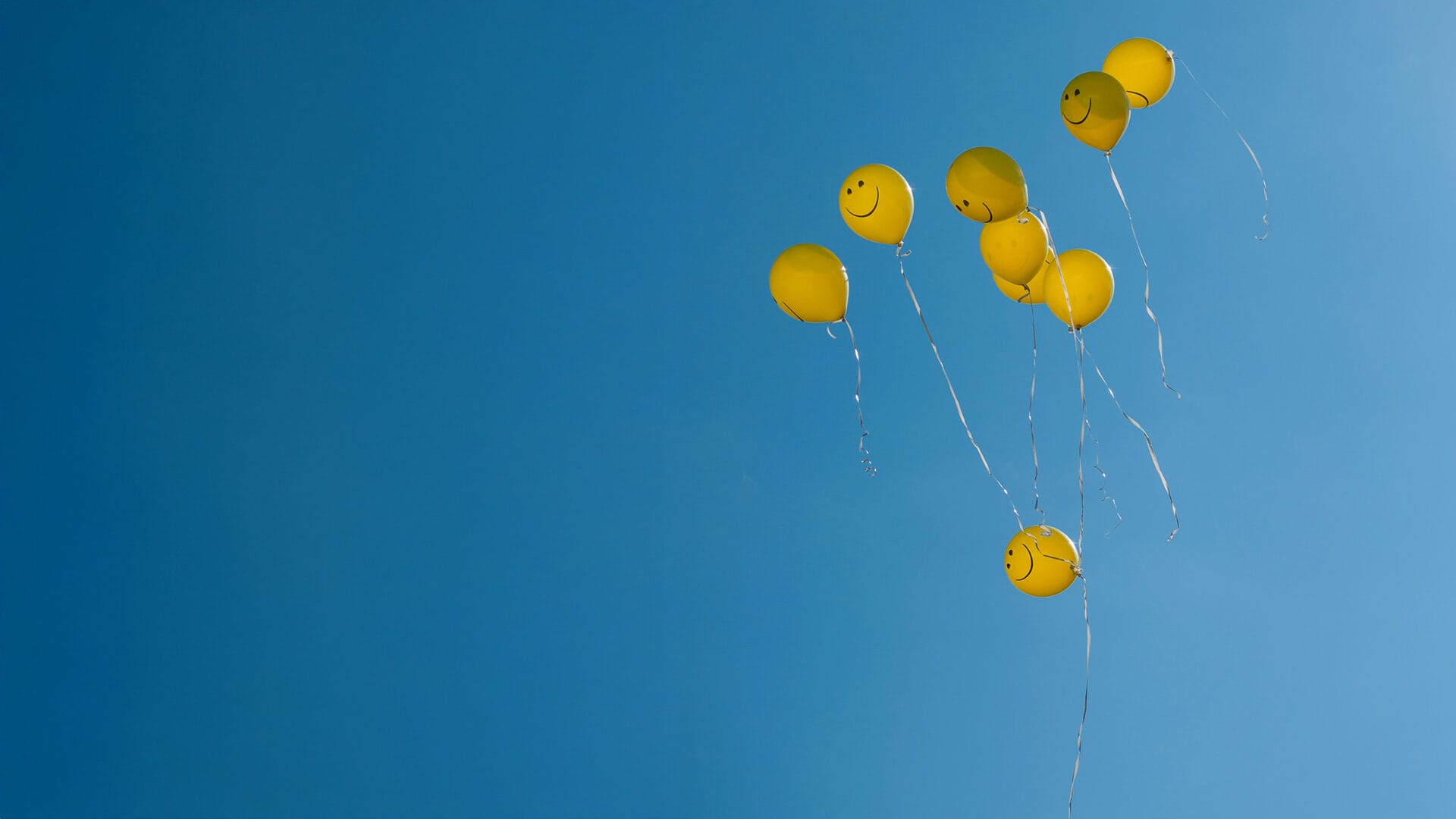 Smiley Ballons in blauem Himmel