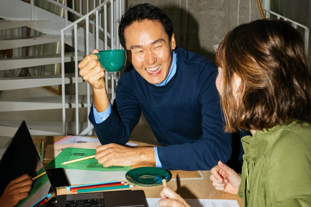 zwei Personen lachen am Schreibtisch