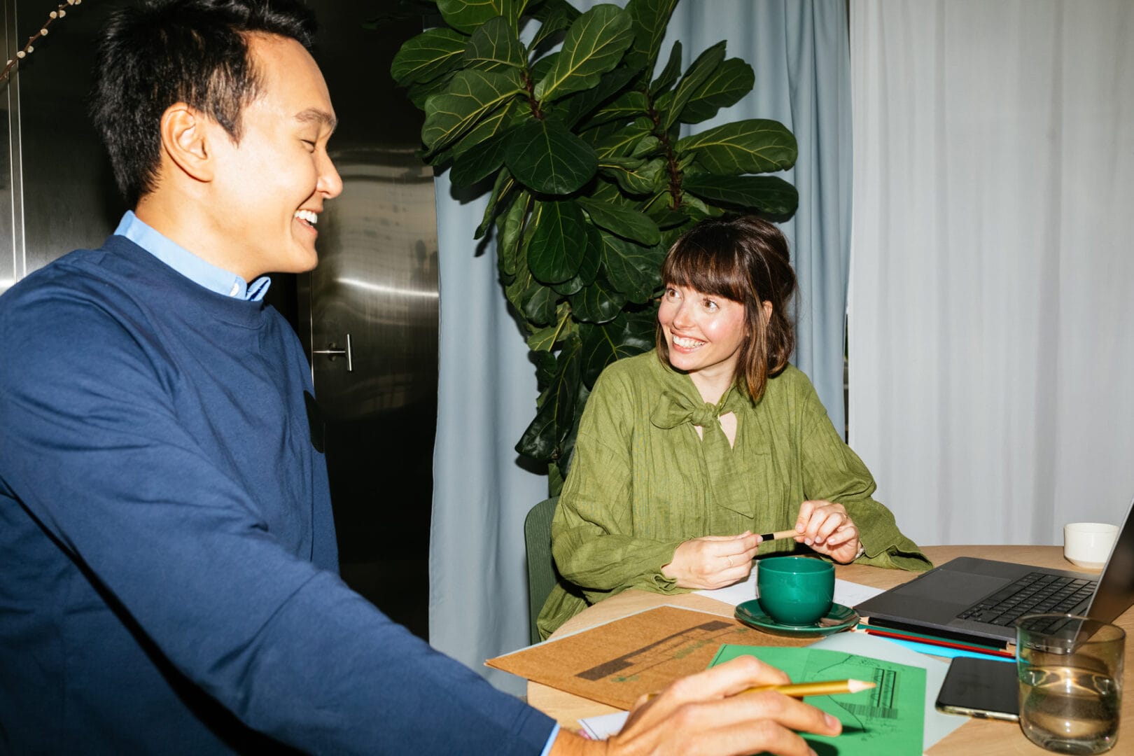 zwei Personen lachen am Schreibtisch